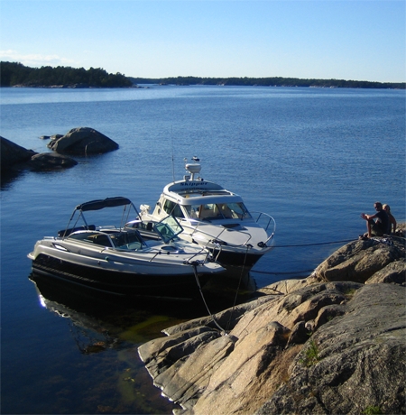 Fritidsbåt i skärgården nära klippor och grunt vatten.